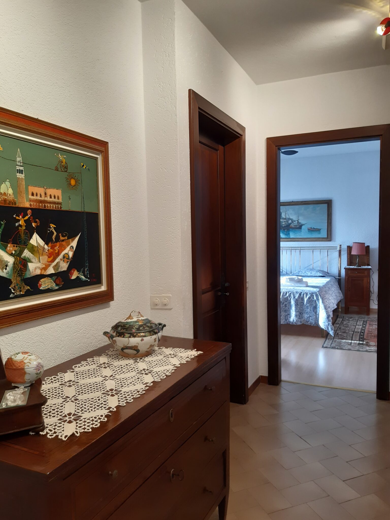 Gemütlicher Innenbereich der Ferienwohnung in Cabbio mit Blick auf das Schlafzimmer und traditionellen Holzmöbeln.