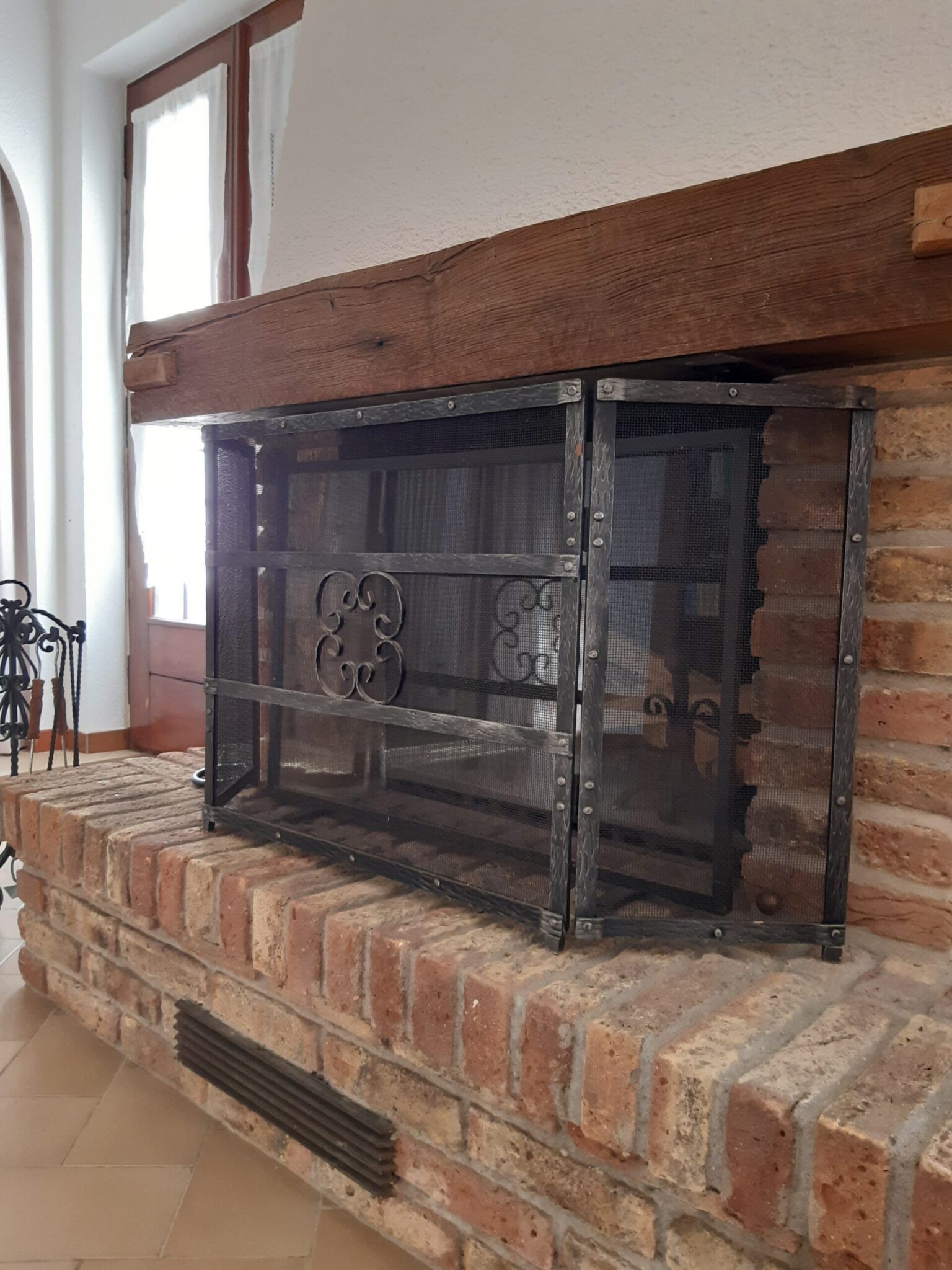 Rustikaler Kamin im Wohnzimmer der Ferienwohnung in Cabbio mit Backstein und Holzdetails.