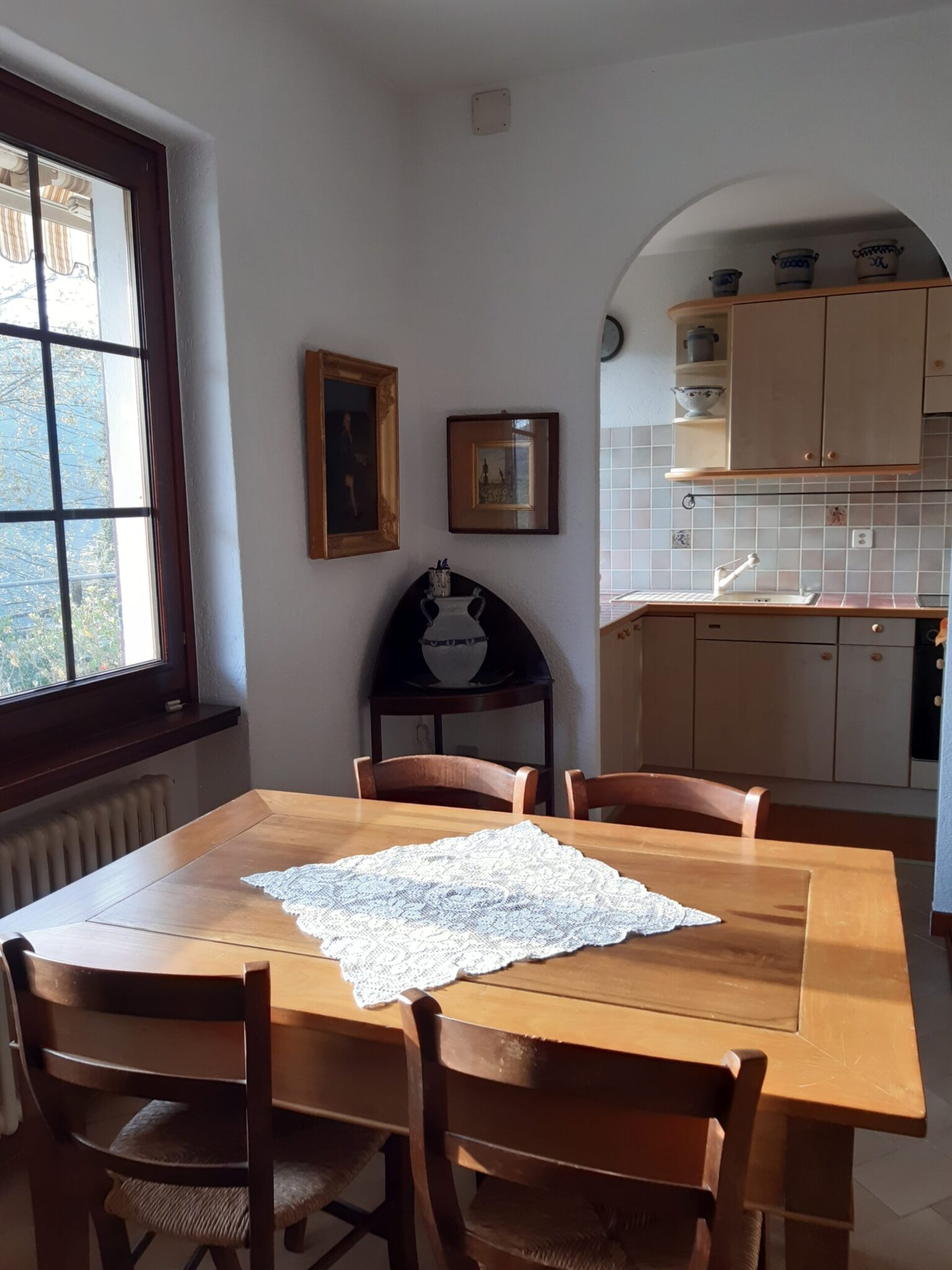 Helles Esszimmer der Ferienwohnung in Cabbio mit Holztisch und Blick zur Küche.