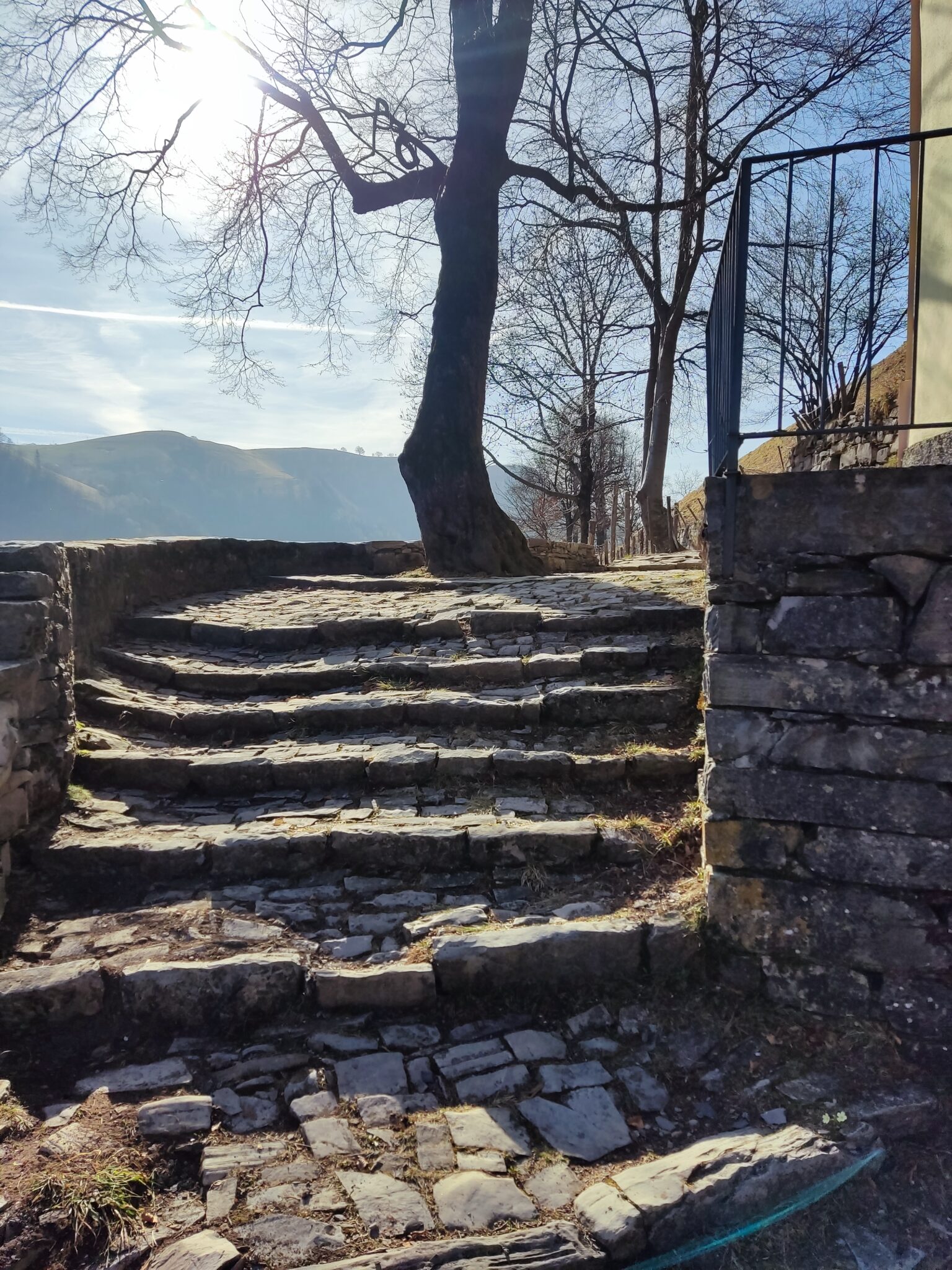 Historische Steintreppe auf einem Wanderweg in der Valle di Muggio im Tessin mit Blick auf die umliegende Berglandschaft